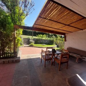 un patio con pérgola de madera, mesa y sillas en Yanasuspa Huasin & Sol del Pilar en Tafí del Valle