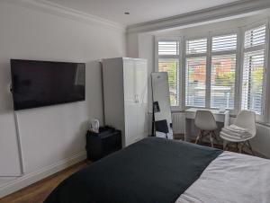 um quarto com uma cama e uma televisão de ecrã plano em Luxury Hotel Rooms em Palmers Green