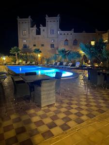 a swimming pool at night with tables and chairs at Kasbah Ait BenHadda in Skoura