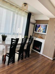 a dining room with a table and chairs and a television at Apartament Promenada in Craiova