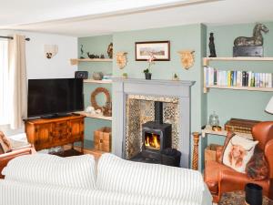 a living room with a fireplace and a tv at Victory Hall Cottage in Spilsby