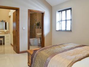 a bedroom with a bed and a bathroom with a sink at The Old Stables in South Cave