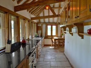 a large kitchen with wooden ceilings and a table at Romden Barn in Smarden