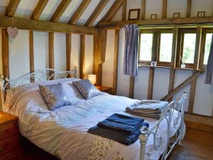 a bed in a room with wooden walls and windows at Romden Barn in Smarden