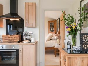 a kitchen with a counter and a room with a bed at Holders Cottage in Lassington