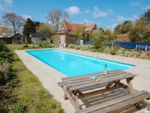 a wooden picnic table next to a swimming pool at Chere Amie-qu7616 in Melton Constable