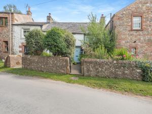 an old stone house with a fence and a street at Townhead Cottage in Newbiggin