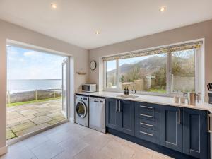 a kitchen with blue cabinets and a view of the ocean at Y Beudy Gwydir in Trevor
