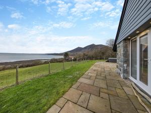 a stone pathway next to a house with a view of the ocean at Y Beudy Gwydir in Trevor