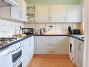 una cocina con armarios blancos y electrodomésticos blancos en Meadowfield View, en Ryton
