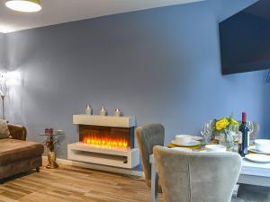 a living room with a fireplace with a table and chairs at Daisy By The Sea in Scarborough