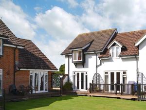 una casa con paredes blancas y techos marrones en Pottergate Cottage, en Wroxham