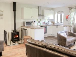 a kitchen and living room with a couch and a fireplace at The Old Parlour in Sedlescombe