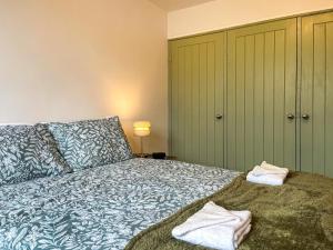 um quarto com uma cama com lençóis azuis e verdes em Pennies Retreat em Glossop