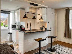 a kitchen with two bar stools and a counter at Pennies Retreat in Glossop