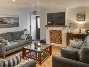uma sala de estar com sofás e uma lareira com televisão em Jock Mcmuffin Cottage em Portknockie