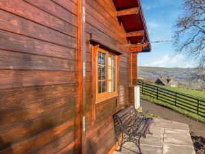 un bâtiment en bois avec un banc à côté d'une fenêtre dans l'établissement Crown Hill Lodge, à Cononley