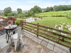 a patio with a table and chairs and a fence at Molehill Lodge in Ammanford