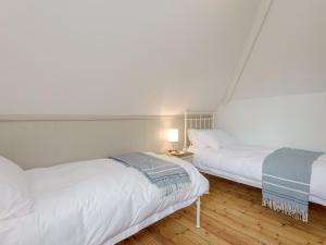 a bedroom with two beds and a table with a lamp at Stable Yard Cottage in Selborne