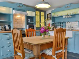 a kitchen with blue cabinets and a wooden table and chairs at Sunnyside in Delabole