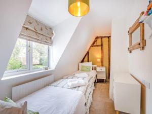 two beds in a room with a window at Inglenook in Corpusty