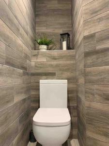 a bathroom with a white toilet in a wooden wall at Central Skipton - Devonshire Court Apartment 2 in Skipton