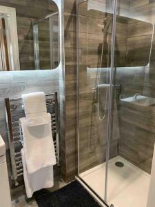 a bathroom with a shower and a sink with towels at Central Skipton - Devonshire Court Apartment 2 in Skipton