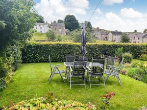 a table and chairs with an umbrella in a yard at Beech Cottage - Uk44731 in Hartington