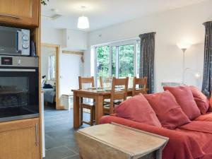 a living room with a red couch and a table at Bridge Cottage in Earlston