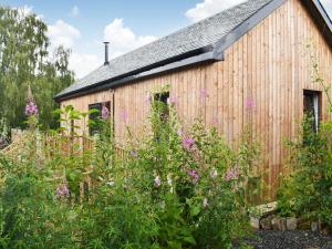 a wooden building with flowers in front of it at Bridge Cottage in Earlston