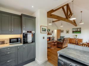 a kitchen with gray cabinets and a living room at Barn Cottage in Falfield