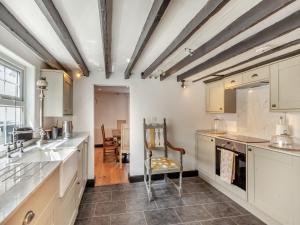 a kitchen with white cabinets and a table at Cutters Cottage in Roydon