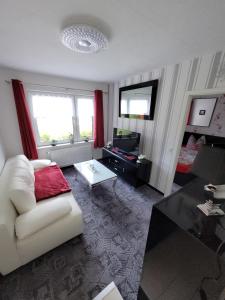een woonkamer met een witte bank en een tafel bij Ferienwohnung 1 - a72143 in Wangerland