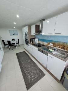 a kitchen with white cabinets and a sink and a table at Ferienwohnung 1 - a72143 in Wangerland
