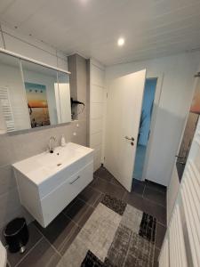 een badkamer met een witte wastafel en een spiegel bij Ferienwohnung 1 - a72143 in Wangerland