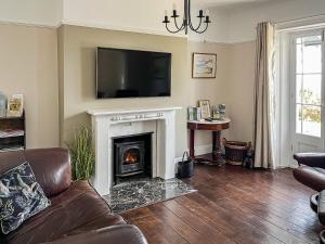 a living room with a fireplace with a television above it at Coastguards in Ventnor