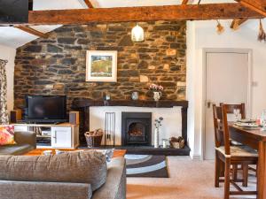 a living room with a stone wall with a fireplace at The Stables in Sedbergh