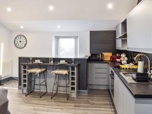 a kitchen with a counter and a kitchen island with bar stools at Skiddaw View Cottage - Uk44655 in Cockermouth