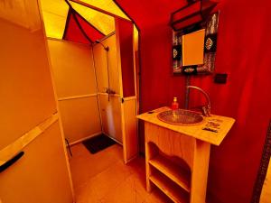 un bagno rosso con lavandino e doccia di Berbers Luxury Camp a Merzouga