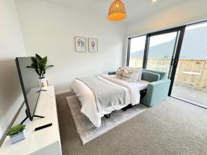 a bedroom with a bed and a couch and window at Zen hideaway in Aotea in Porirua