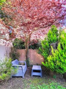 een tuin met twee stoelen en een tafel en een boom bij Coin de Paradis in Saint-Leu-la-Forêt