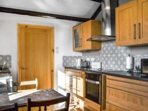 a kitchen with wooden cabinets and a table in it at The Old School House in Sunk Island