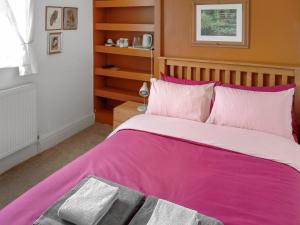 a bedroom with a pink bed and a window at The Old School House in Sunk Island