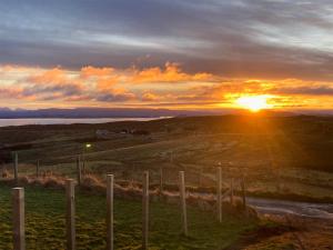 a sunset over a field with a fence at 3 Breckery in Staffin