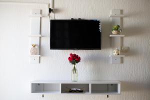 une télévision suspendue sur un mur avec un vase de fleurs dans l'établissement BEAU SÉJOUR hébergement et spa, à Gabès