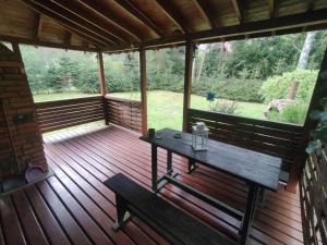 una veranda in legno con tavolo e panca di Klimatyczny domek w lesie przy jeziorze a Gietrzwałd