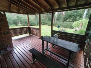 a wooden porch with a table and a bench on it at Klimatyczny domek w lesie przy jeziorze in Gietrzwałd