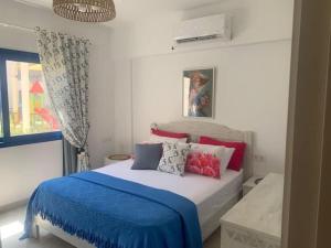 a bedroom with a bed with a blue blanket and pillows at Marassi in El Alamein