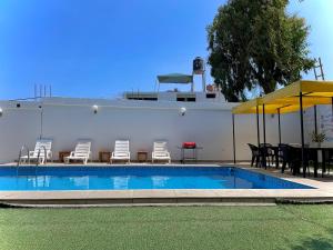 a swimming pool with chairs and a table and umbrella at HUANCHACO GARDENS in Huanchaco