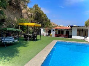 einen Pool mit einem Tisch und einem gelben Sonnenschirm in der Unterkunft HUANCHACO GARDENS in Huanchaco